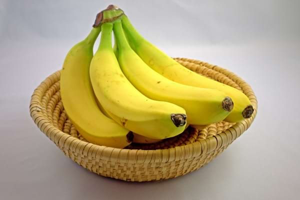 Régime de bananes jaunes mûres dans une corbeille en osier.