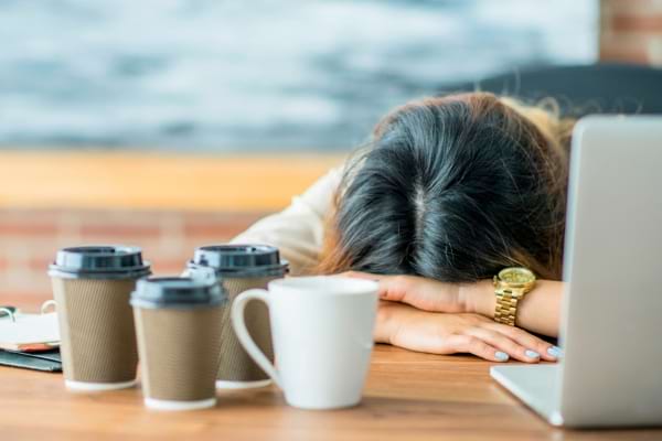 Une femme affalée sur son bureau par fatigue