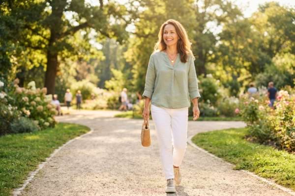 'une femme souriante et en pleine forme se promenant dans un parc ensoleillé