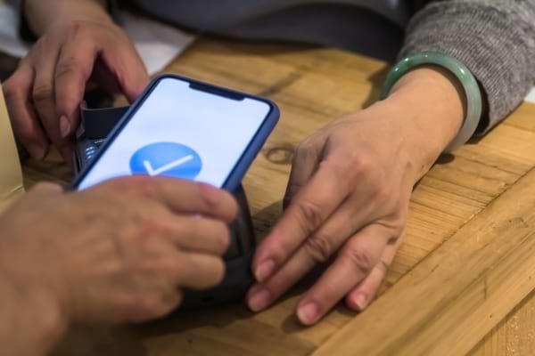 Une personne qui paie avec son téléphone sans contact