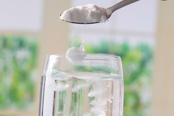 Bicarbonate de soude versé dans un verre d’eau.