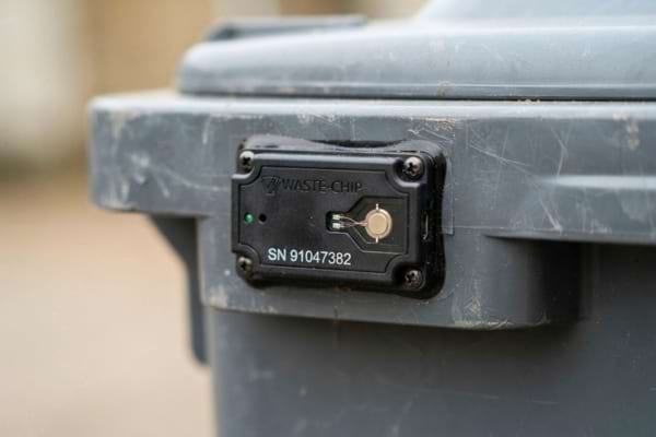 une puce électronique noire fixée sur le plastique d'une poubelle grise