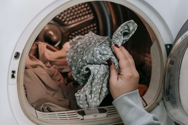 Personne plaçant du linge dans le tambour d’une machine à laver.