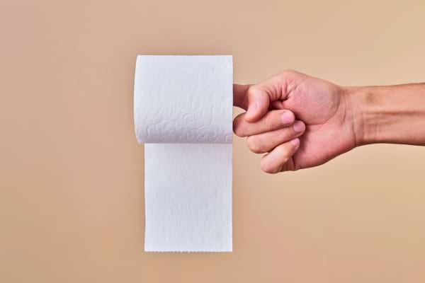 Un rouleau de papier toilette tenu par un doigt