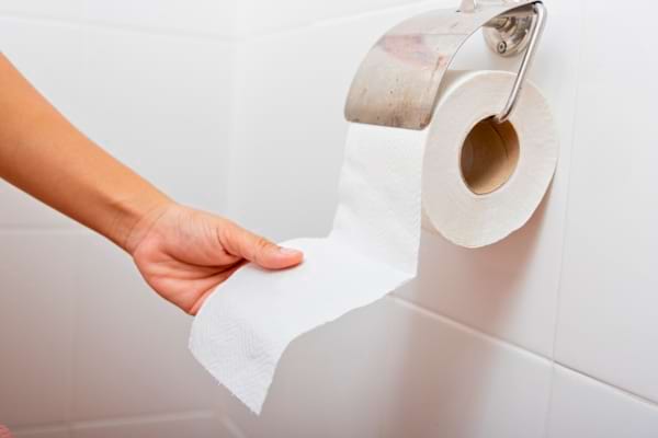 Personne qui tire du papier toilette par le haut