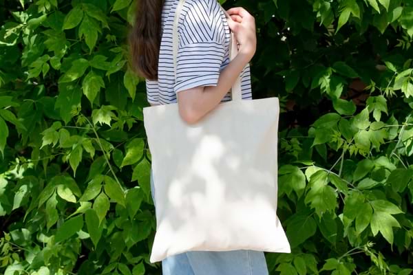 Grand sac à main en tissu blanc porté par une femme sur l'épaule