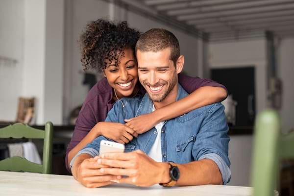 Un couple heureux qui regarde un t&eacute;l&eacute;phone