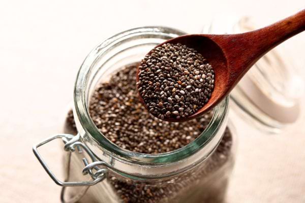 pot de graines de chia avec une cuill&egrave;re en bois pour les bienfaits au quotidien