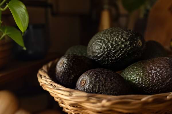 Avocats conservés dans un panier en osier, à l’abri de la lumière dans la cuisine.