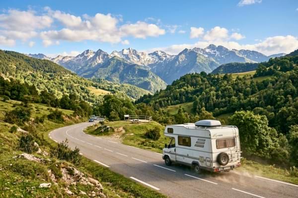 un vieux camping-car blanc roulant sur une petite route de montagne sinueuse dans les Pyr&eacute;n&eacute;es