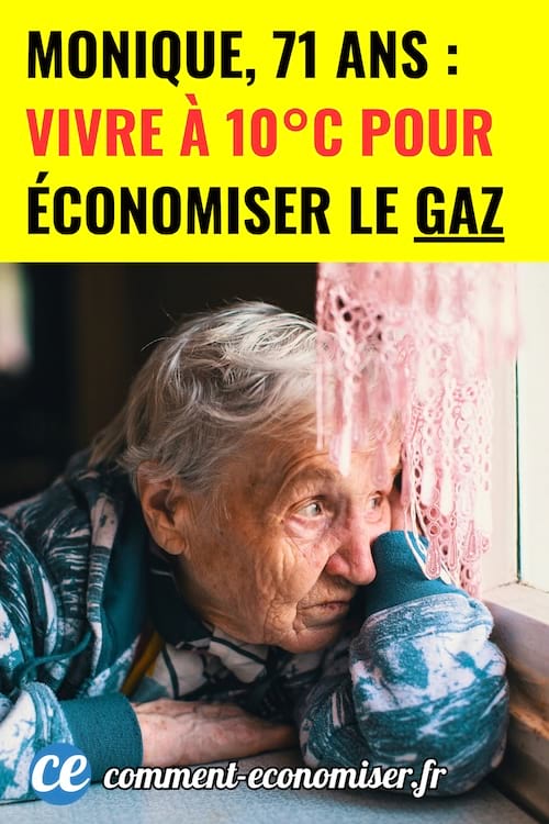 une vieille femme avec un pull bleu épais regarde par la fenêtre l'air triste