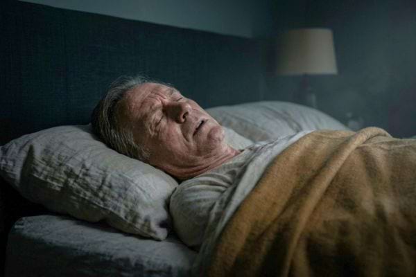 an older man sleeping in bed, slightly tense facial expression, dark night atmosphere