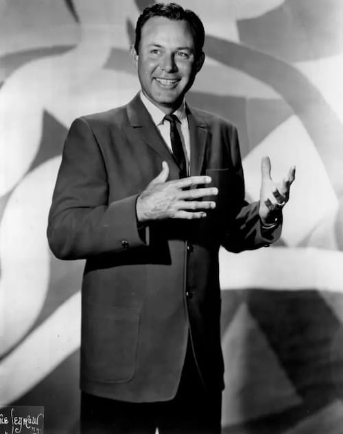 portrait en pied noir et blanc de Jim Reeves souriant s'apprêtant à chanter