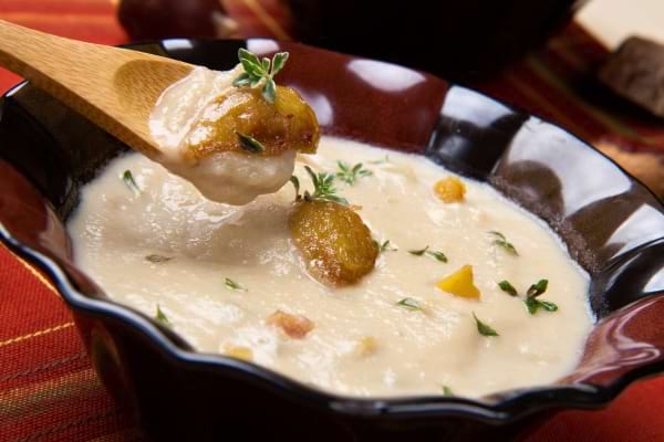 un velouté de chataîgnes crémeux dans une assiette rouge avec une cuillère en bois