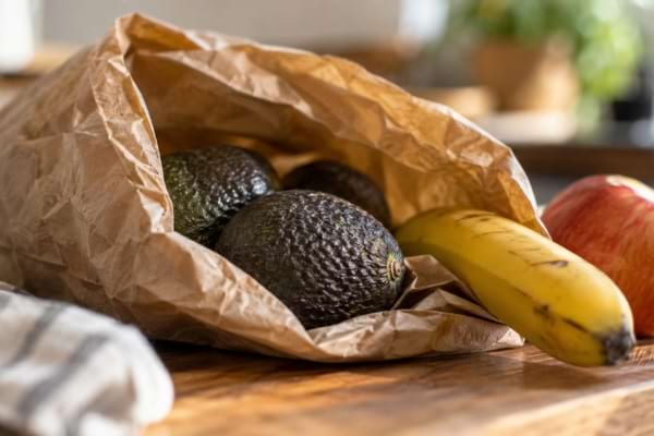 Avocats dans un sac en papier avec une banane et une pomme pour accélérer leur maturation.