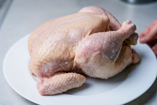 un poulet cru décongelé, montrant la texture de la peau avec quelques zones légèrement blanchies par le froid