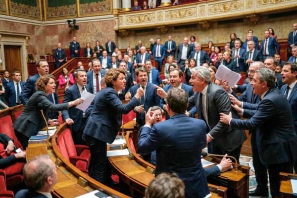 l'hémicycle de l'Assemblée nationale française, députés debout montrant des signes de désaccord