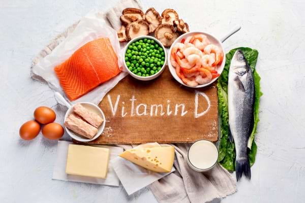 des aliments contenant de la vitamine D sur une planche en bois : saumon, oeuf, crevettes
