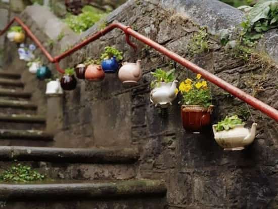 Des théières recyclées et accrochées sur un escalier