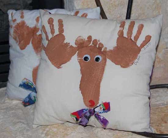 un coussin décoré avec des empreintes de pieds et de mains pour noel