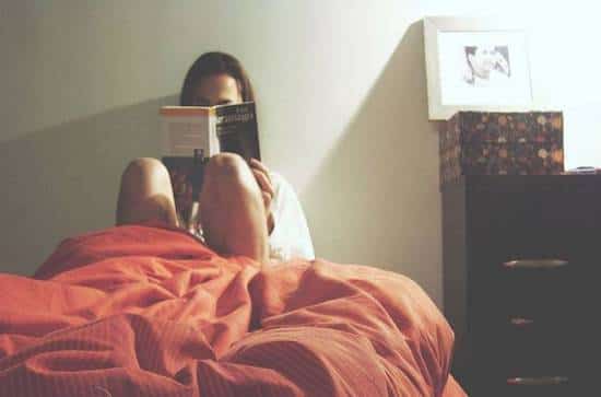 Femme en train de lire un livre au lit