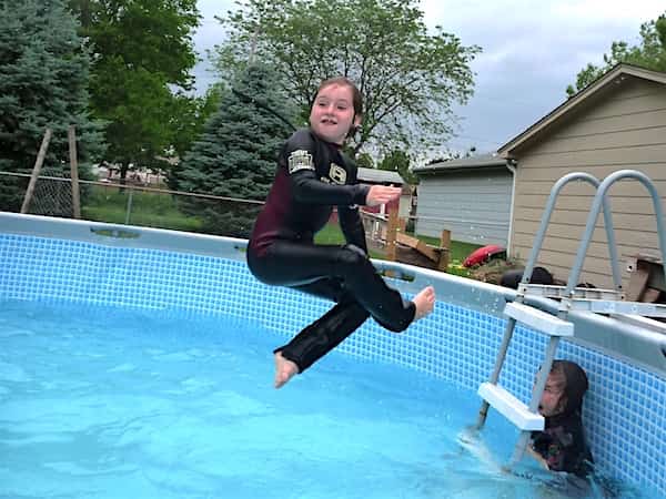 Enfant qui saute dans la piscine et sa soeur qui a peur