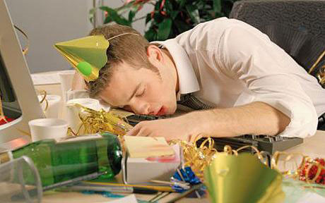 Un homme dormant sur son bureau avec un chapeau de fête