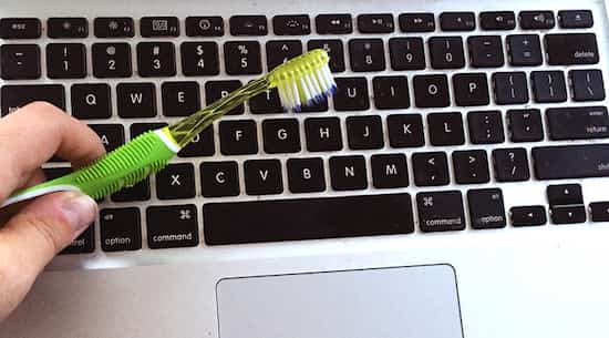 nettoyer le clavier d'un ordinateur avec une brosse à dents