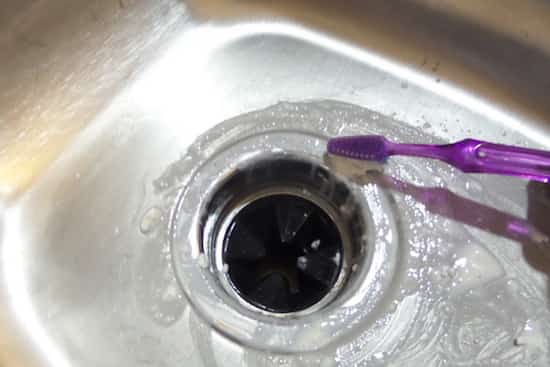 Une brosse à dents pour nettoyer un siphon