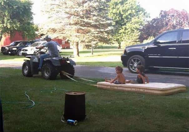 sur son quad, un papa tire un matelas sur lequel il y a ses enfants