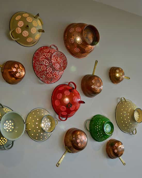 passoires recyclées et accrochées au mur en lampe