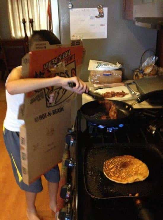 un homme qui fait la cuisine avec un carton de pizza sur lui