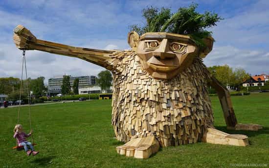 sculpture d'un troll géant en bois tenant une balançoire à bout de bras