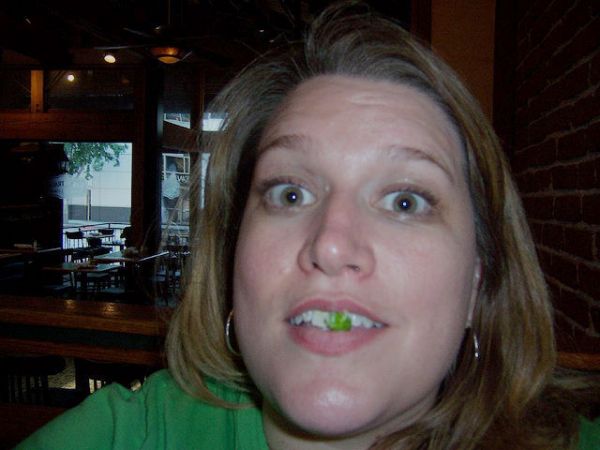 Femme qui sourit avec un truc vert sur les dents