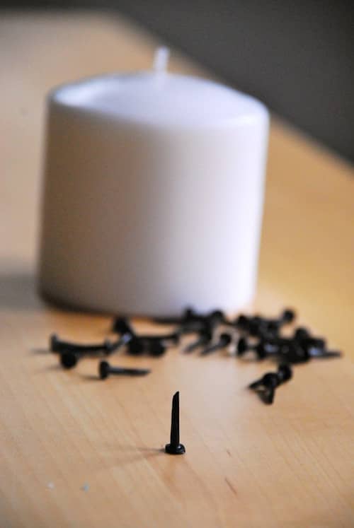 une bougie blanche avec des clous à côté